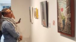 Rektor UII Fathul Wahid memperhatikan salah satu karya lukisan dalam pameran lukisan bertema Dari Indonesia ke Palestina: Refleksi Setahun Tragedi Kemanusiaan, digelar di Gedung Moh. Hatta UII dan akan berlangsung selama satu bulan ke depan. Foto Istimewa.