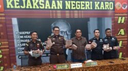 Kasi Intel Kejari Karo Dona Martinus Sebayang bersama Kasi Pidsus Renhard Harve Sembiring memperlihatkan uang Rp900 juta lebih yang diserahkan salah satu tersangka dugaan korupsi distribusi pupuk subsidi Tahun 2022 di Kecamatan Merek, Kabupaten Karo. Foto Rienews.com.