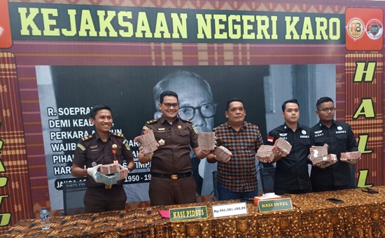 Kasi Intel Kejari Karo Dona Martinus Sebayang bersama Kasi Pidsus Renhard Harve Sembiring memperlihatkan uang Rp900 juta lebih yang diserahkan salah satu tersangka dugaan korupsi distribusi pupuk subsidi Tahun 2022 di Kecamatan Merek, Kabupaten Karo. Foto Rienews.com.