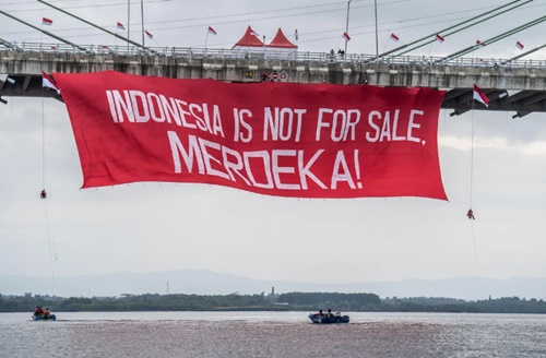 Aktivis Greenpeace membentangkan banner saat aksi damai kreatif di Jembatan Pulau Balang, Kalimantan Timur, yang menjadi pintu masuk ke area IKN, pada 17 Agustus 2023. Aksi damai bersama koalisi masyarakat sipil di Kalimantan Timur ini untuk menyuarakan keresahan akan dampak pembangunan IKN yang merusak lingkungan hidup dan meminggirkan Masyarakat Adat dan lokal. Foto Jurnasyanto Sukarno/Greenpeace.